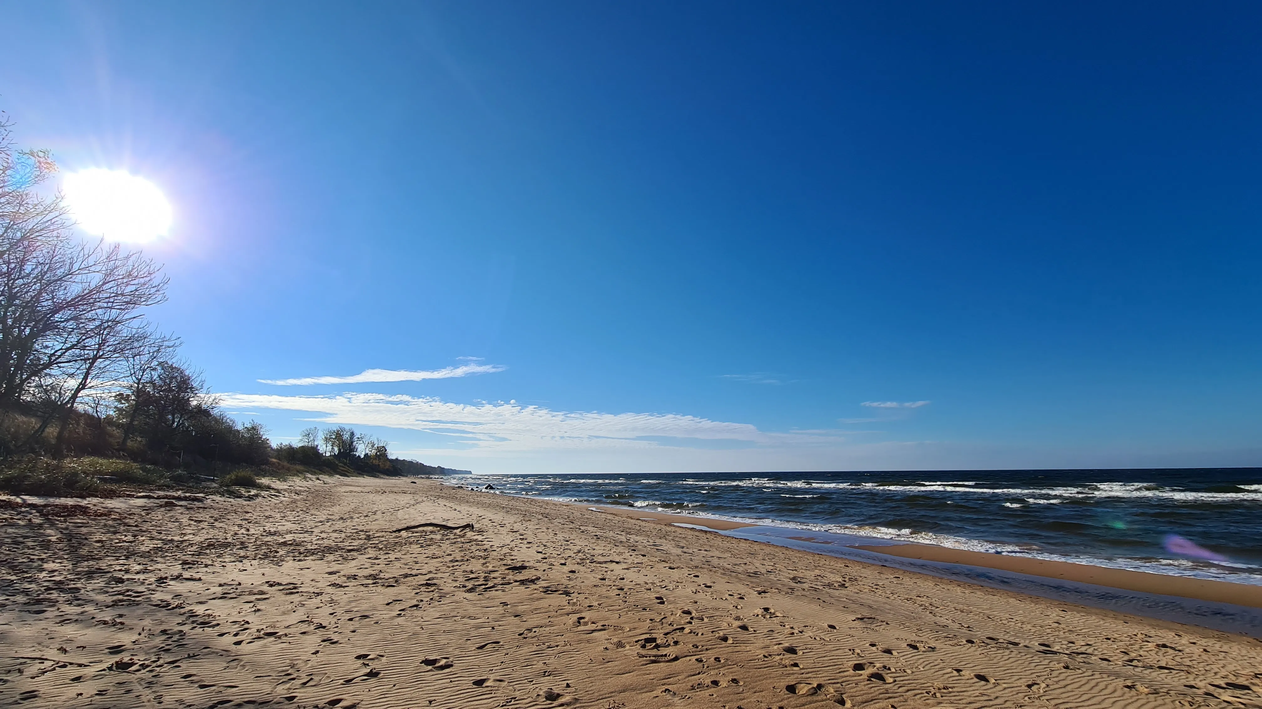 Wide sandy beach with sunlight and gentle waves